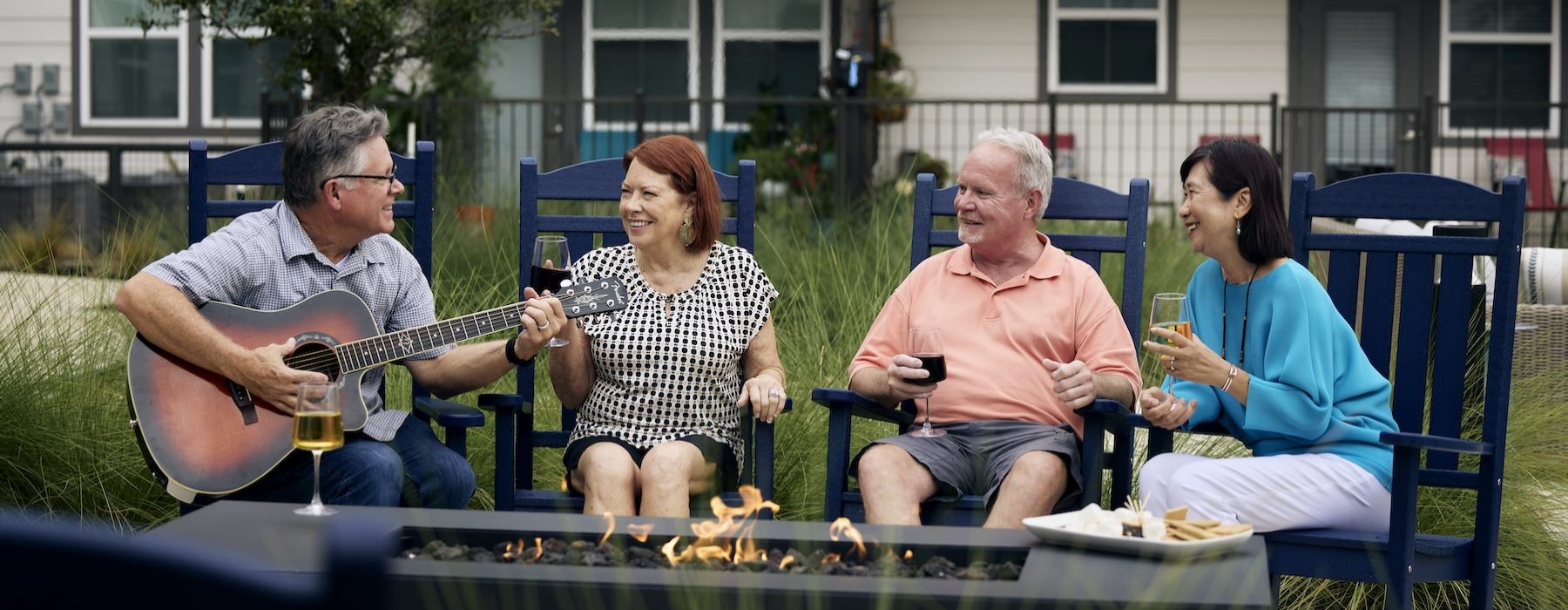 people sitting around fire and a man playing a guitar